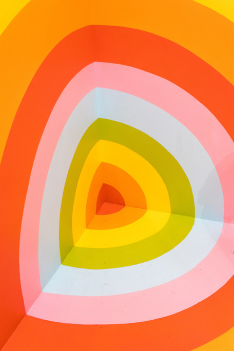A corner painted in different coloured stripes of orange, red, pink, green, yellow and white, so that it appears a bit like a target